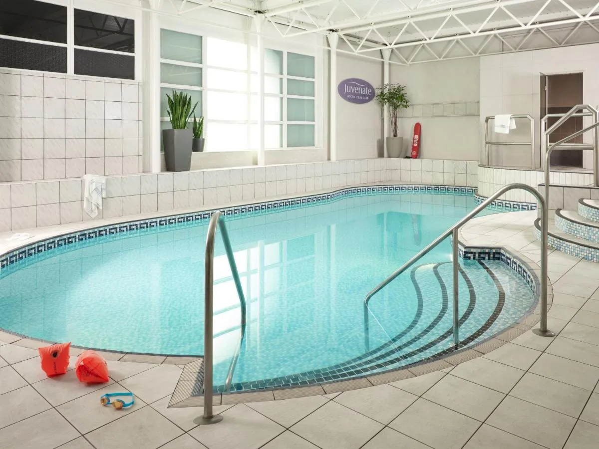 a large swimming pool with stairs in a building at Leonardo Royal Hotel Oxford in Oxford