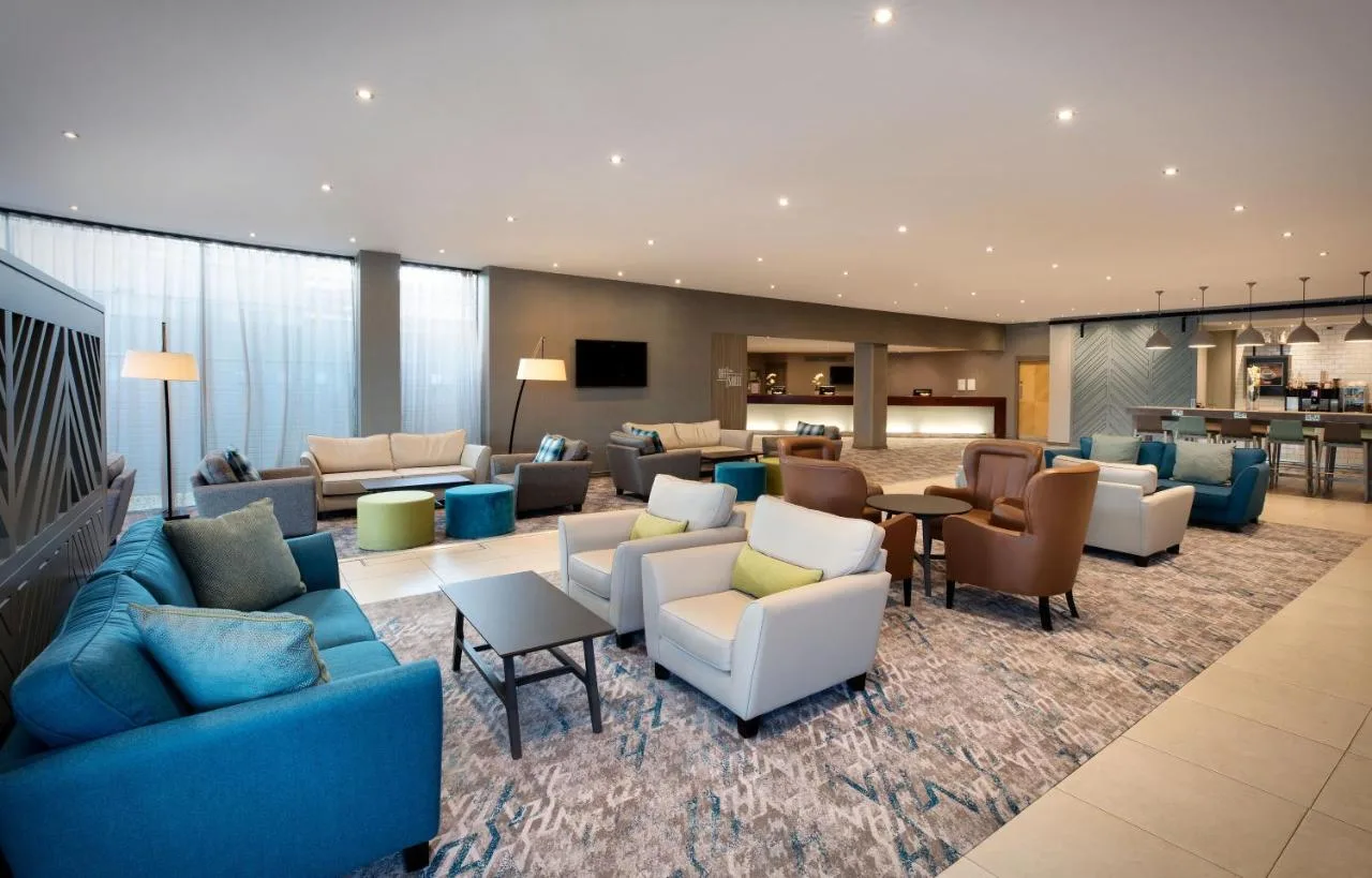 a hotel lobby with couches and chairs and a bar at Leonardo Royal Hotel Oxford in Oxford