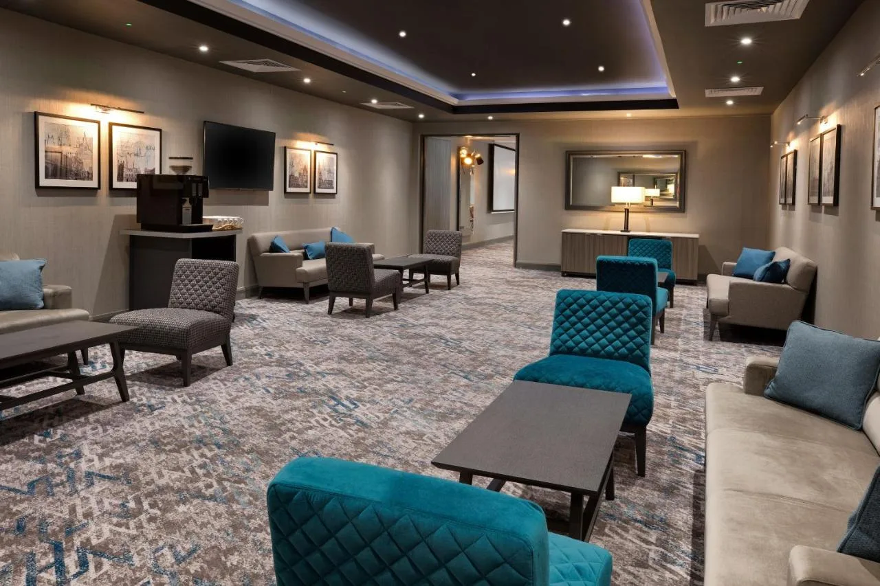 a waiting room with couches and chairs and a tv at Leonardo Royal Hotel Oxford in Oxford
